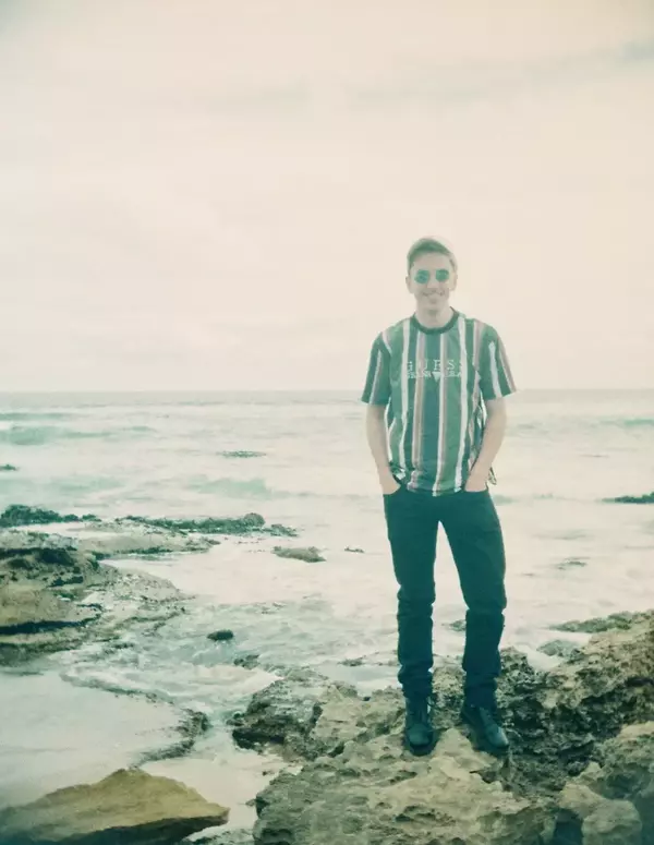 Aaron Campbell, standing on top of rocks at a beach with the ocean in the background, animated stereoscopic wigglegram image